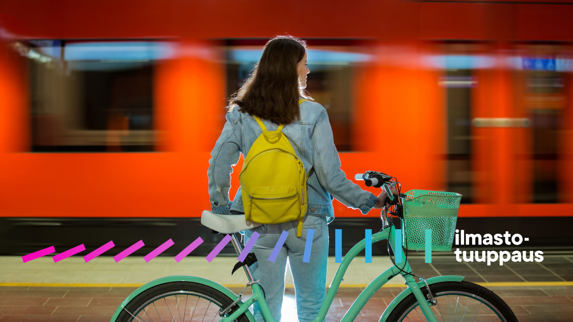 Nainen seisoo pyörän kanssa ja ohi kulkee metro.